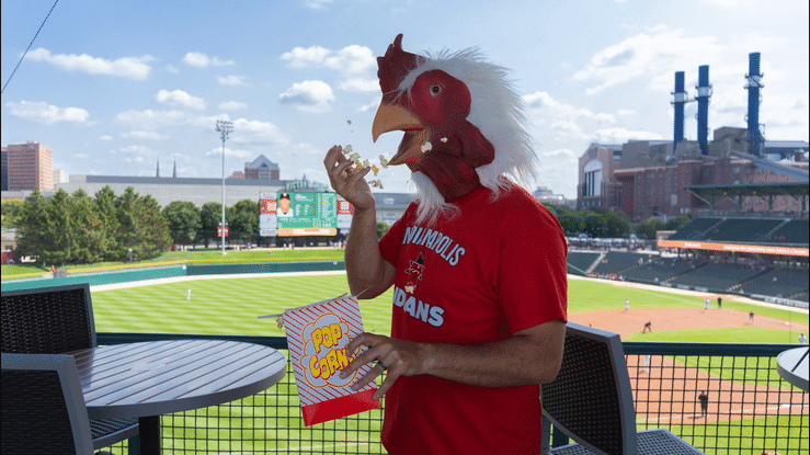 Roger Rooster from Recruit Rooster enjoying popcorn at the ballpark
